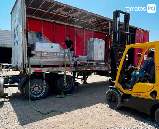 grua descargando productos para ser rematados